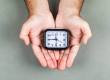 time management clock ticking concept with clock gray background top view hands holding clock horizontal image